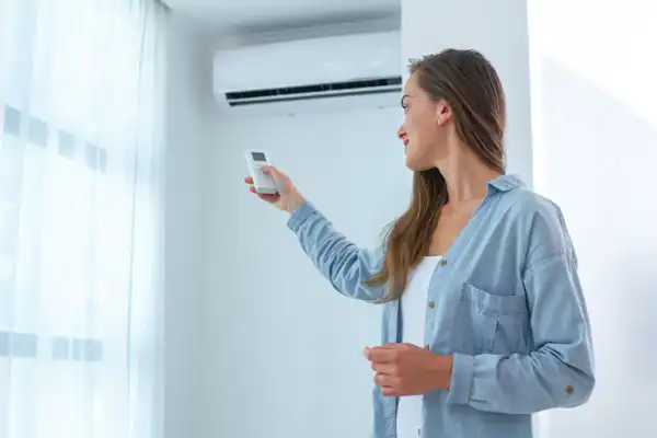 Woman Adjusting the Ductless Mini Split with a Remote Controller