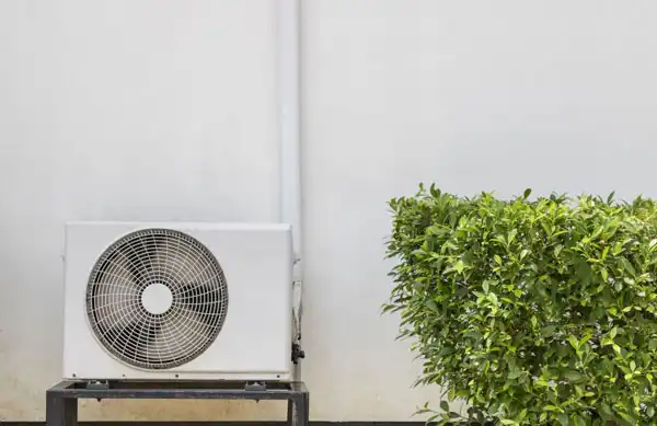 HVAC unit outside next to a bush